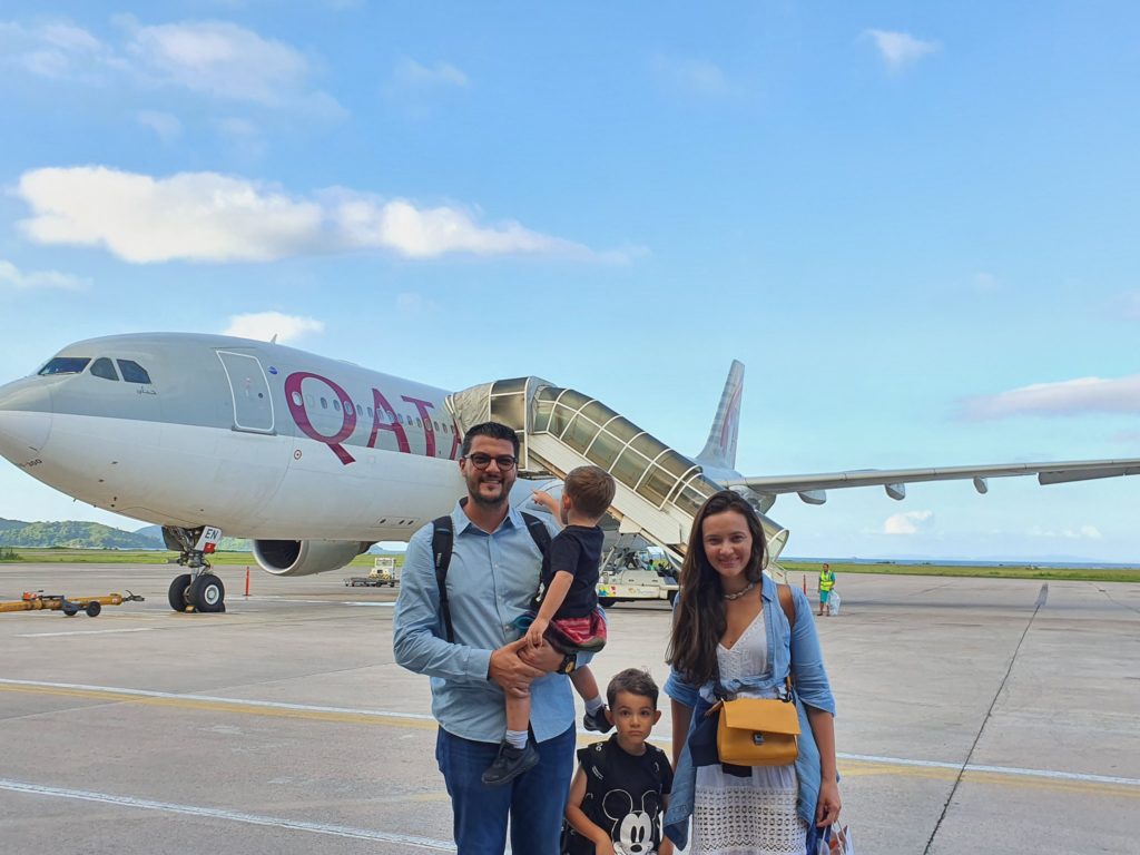 Doi adulți și doi copii în fața unui avion Qatar.