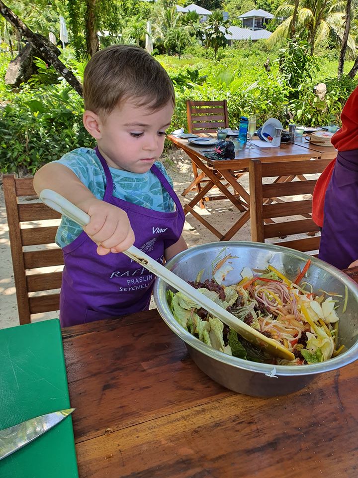 Copil cu șorț amestecând ingrediente într-un bol metalic mare.