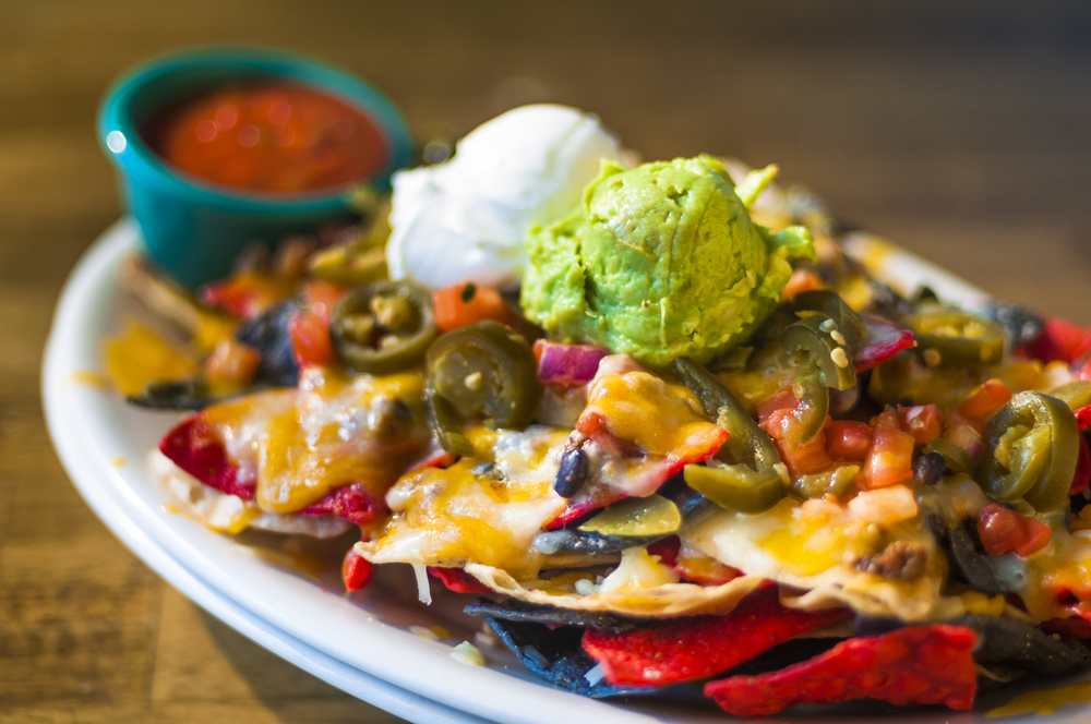 Farfurie cu chipsuri, brânză topită, legume și guacamole.