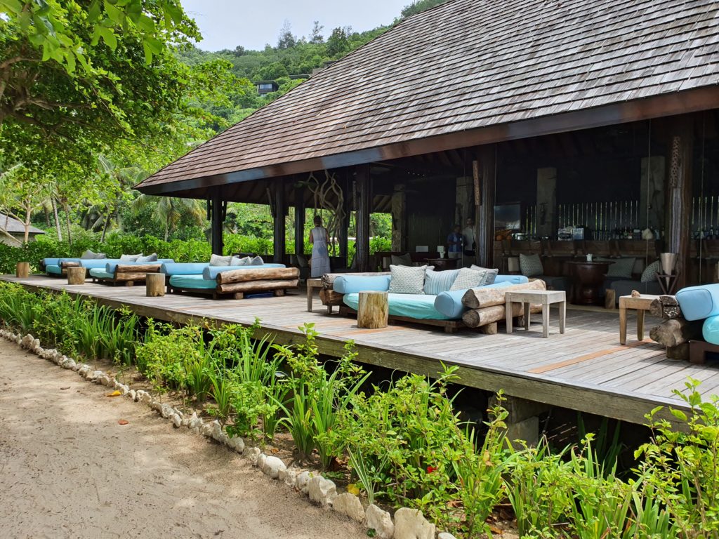 Pavilion deschis cu canapele și șezlonguri lângă o alee.