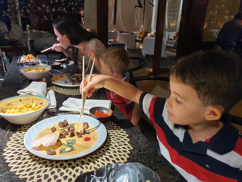 Copii mâncând la masă cu bețișoare asiatice