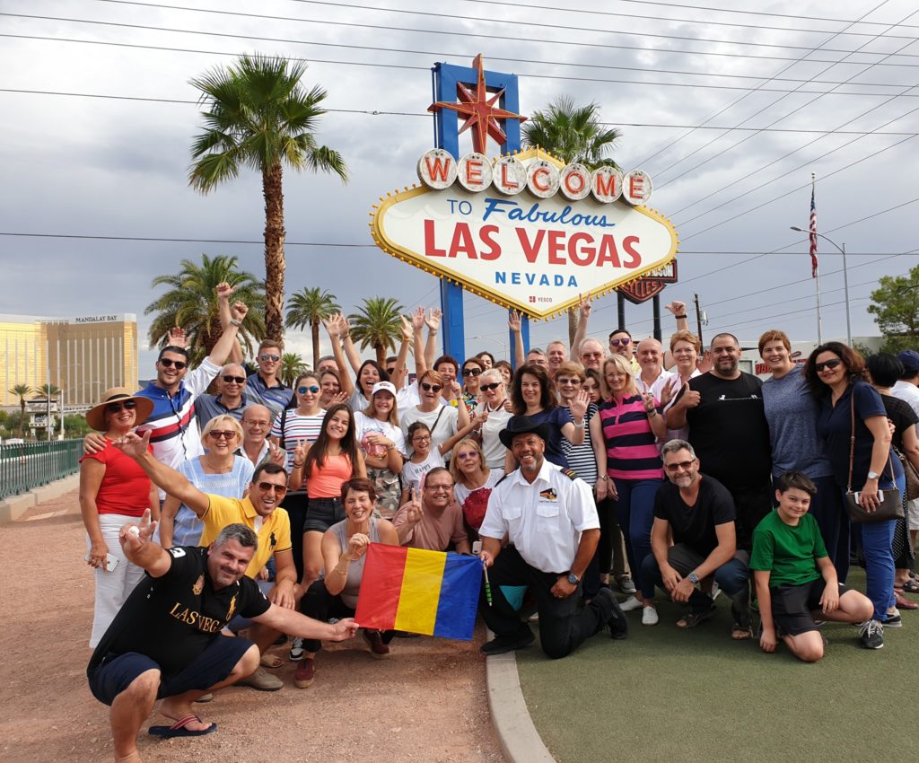 Grup de turiști pozând sub un panou Welcome to Las Vegas.