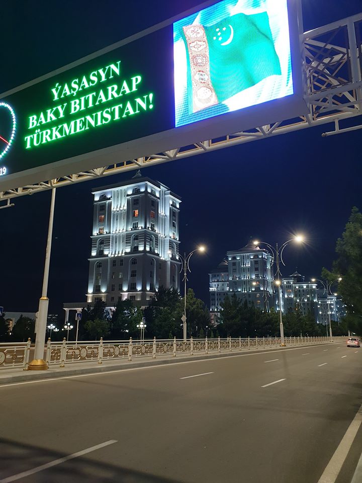 Bulevard nocturn cu panou luminos deasupra carosabilului
