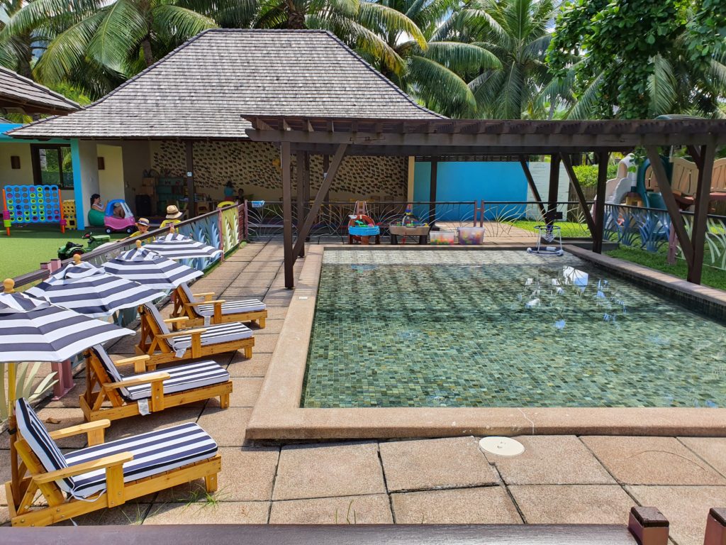 Piscină pentru copii lângă șezlonguri și pavilion din lemn
