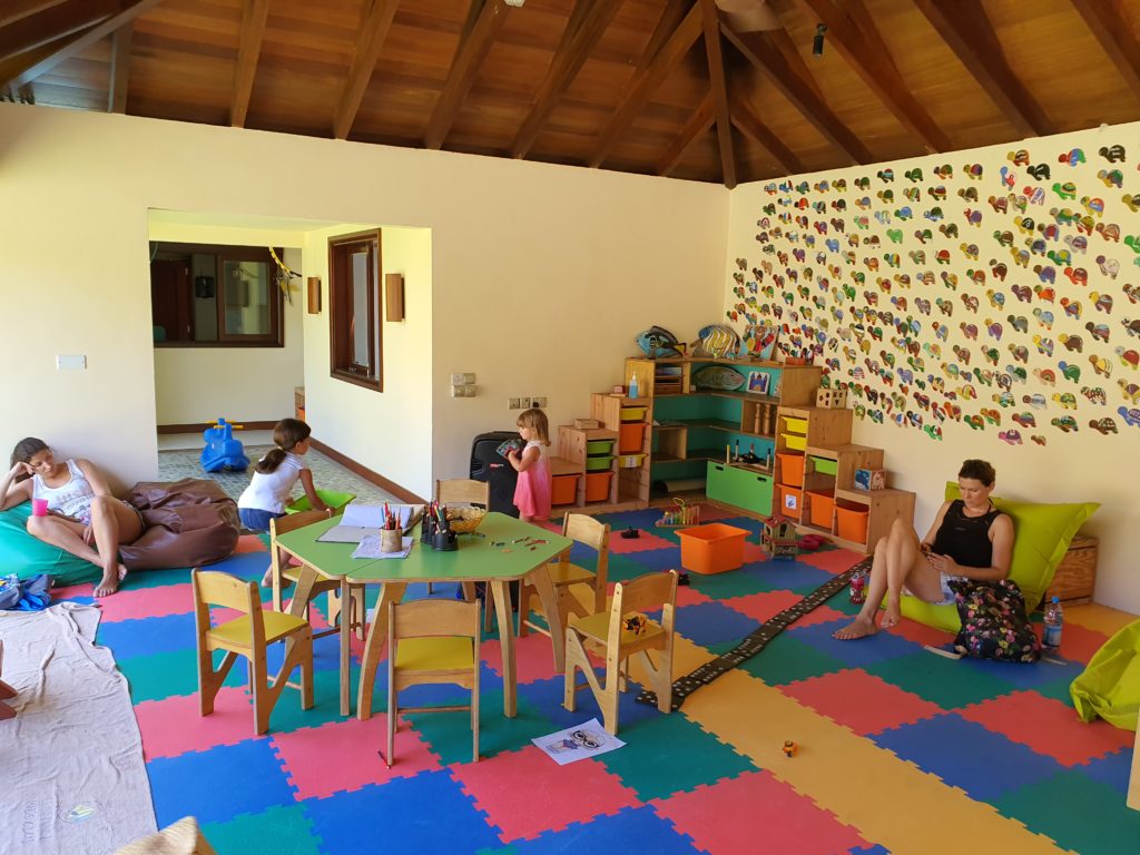 Sală de joacă cu mese mici și covor multicolor
