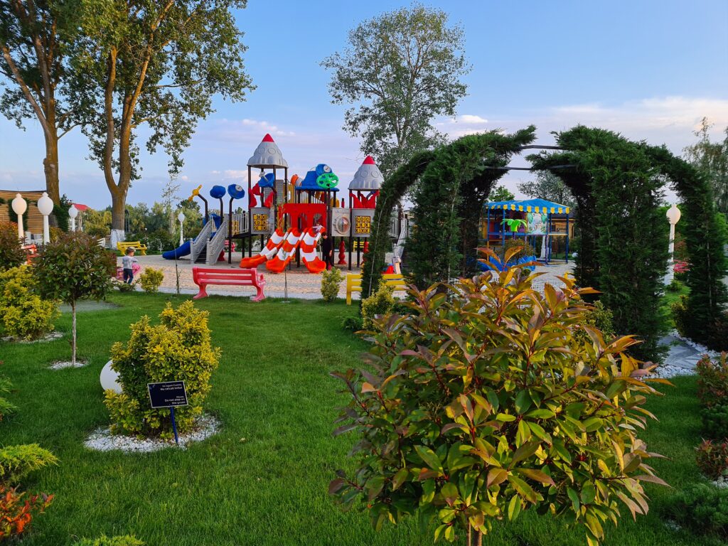 Grădină cu loc de joacă și arcade acoperite de plante