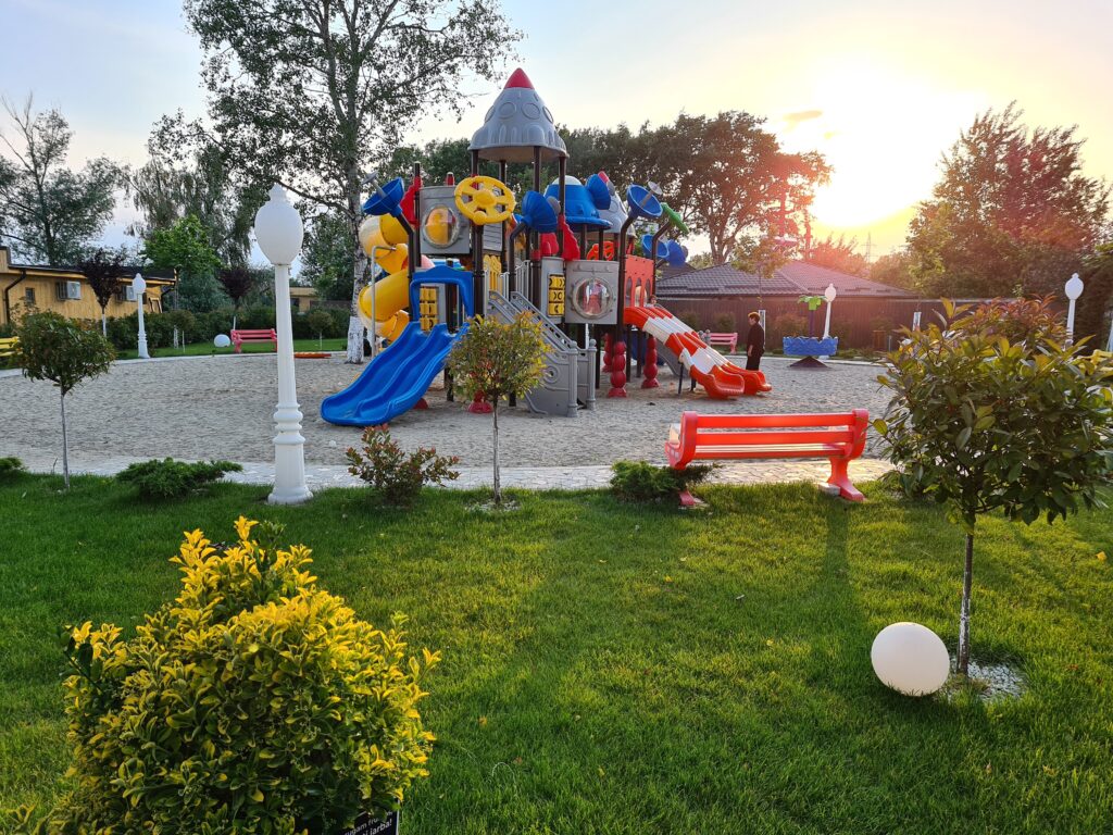 Loc de joacă multicolor într-o grădină la apus
