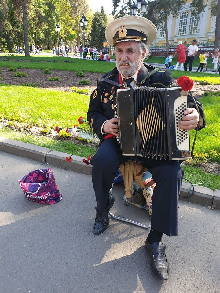 Bărbat cu acordeon așezat pe o bancă în parc