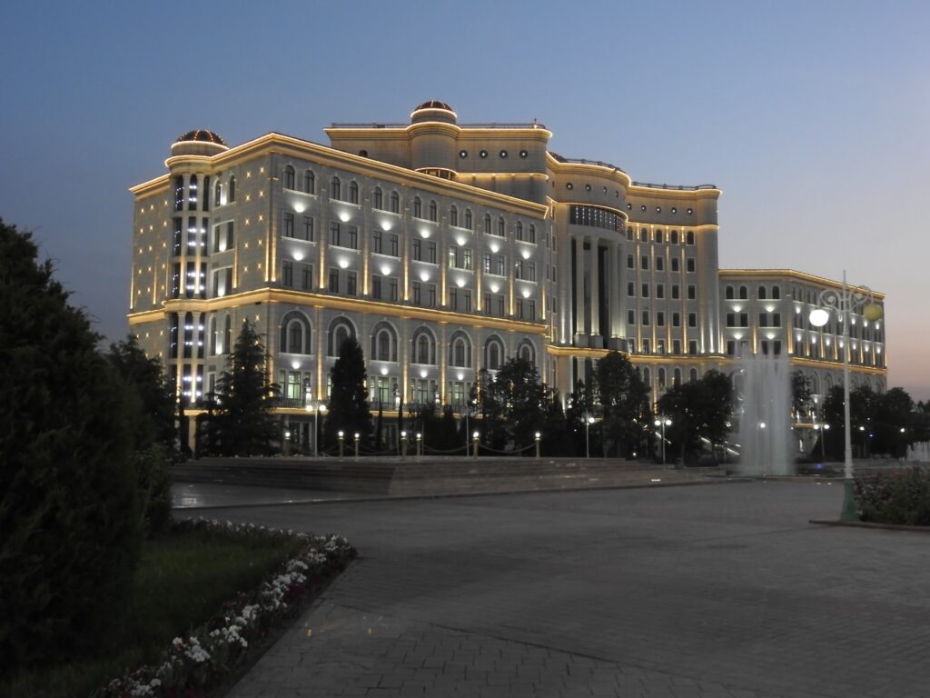 Clădire monumentală iluminată seara, văzută dintr-o piață