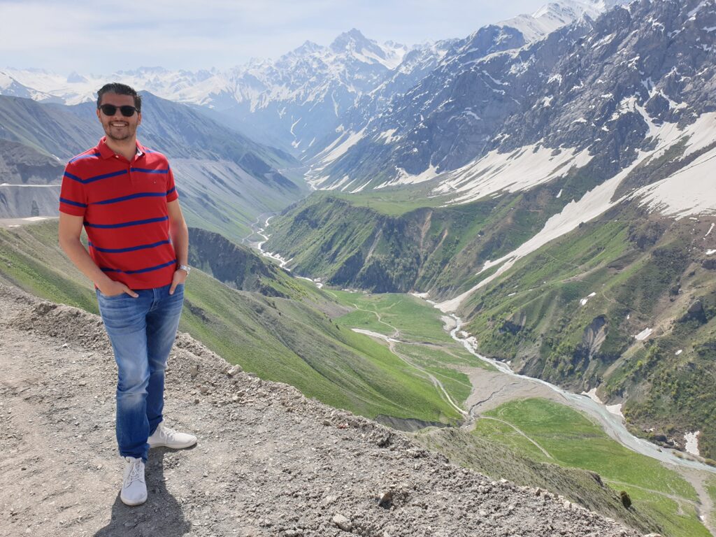 Bărbat pe un versant cu vale montană în fundal