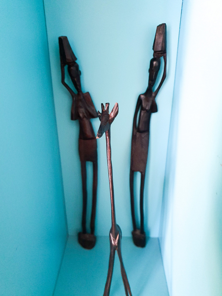 Două figurine alungite din lemn într-o nișă albastră
