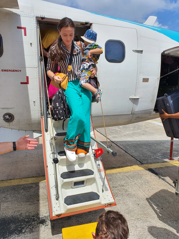 Femeie cu copii coborând pe scara unui avion mic