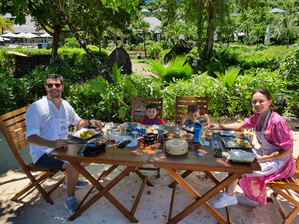 Familie luând masa în aer liber, într-o grădină tropicală