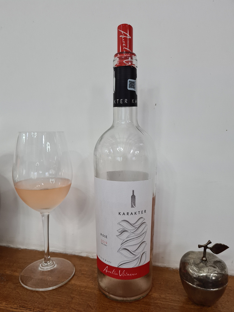 Sticlă și pahar cu vin roze pe un raft