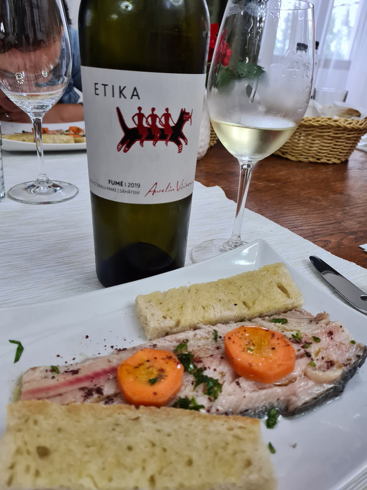 Farfurie cu pește și garnitură lângă sticlă de vin Etika