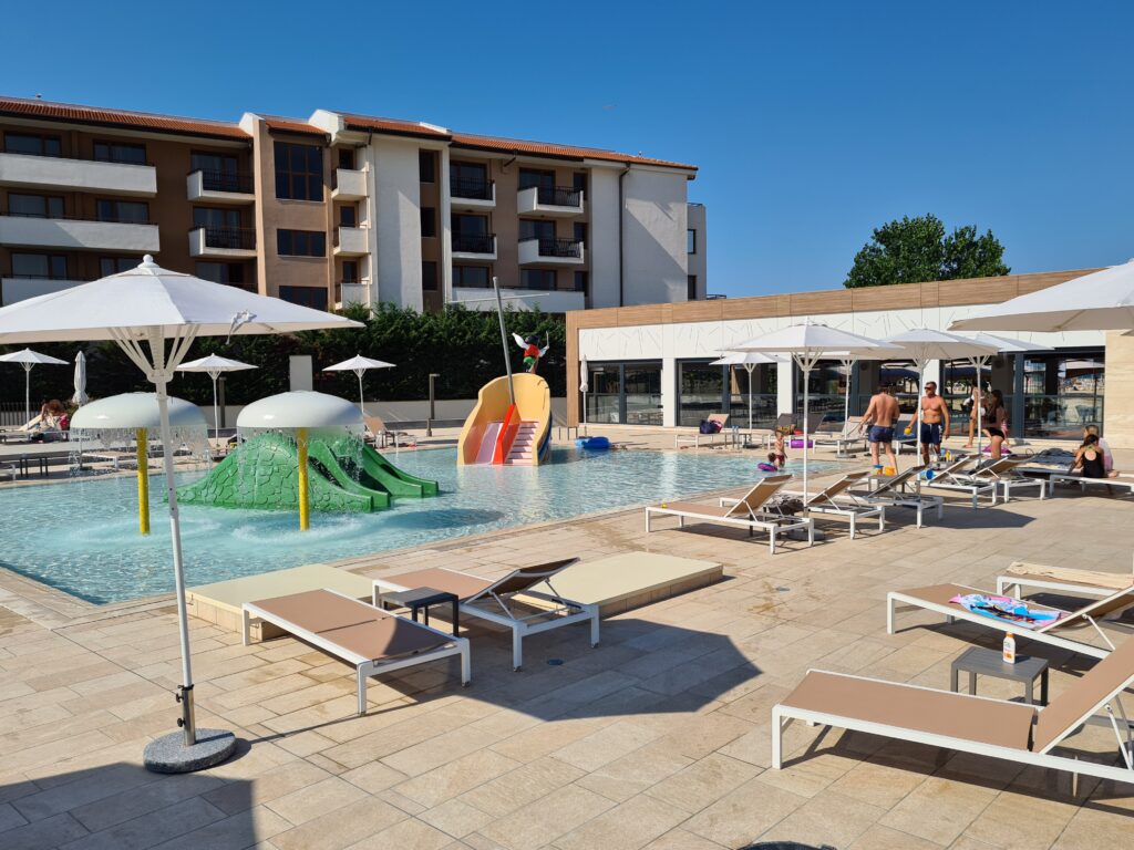 Piscină exterioară cu tobogane, șezlonguri și clădire de hotel
