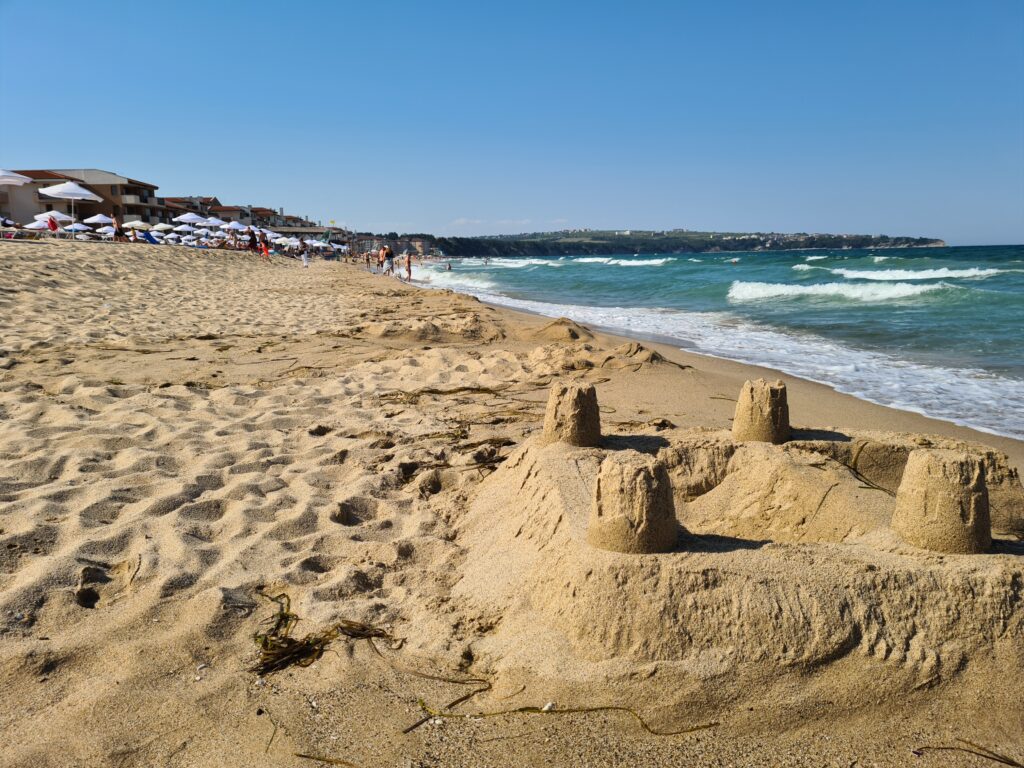 Castel de nisip pe plajă, lângă valurile mării