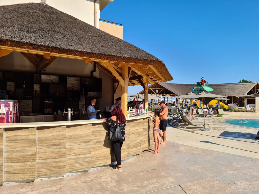 Bar din lemn cu acoperiș de stuf lângă piscină