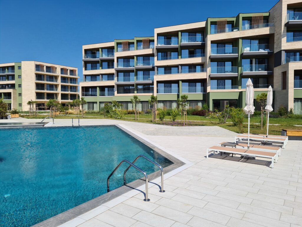Piscină cu scară metalică în fața unei clădiri cu balcoane