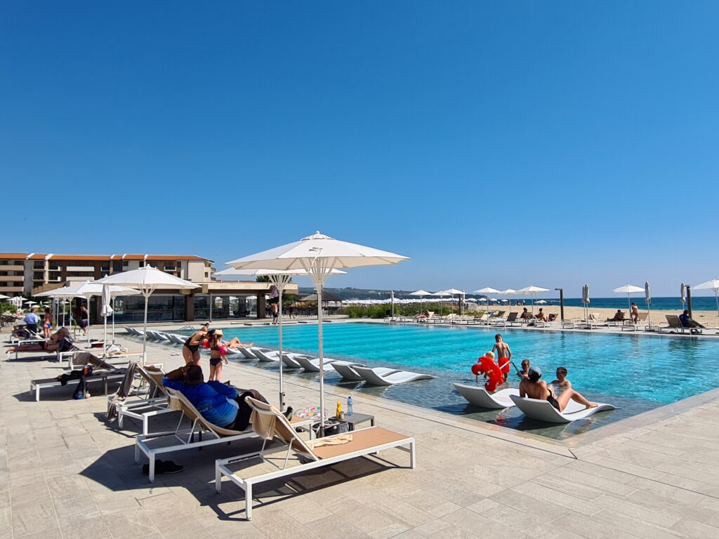 Șezlonguri cu turiști lângă o piscină sub cer senin