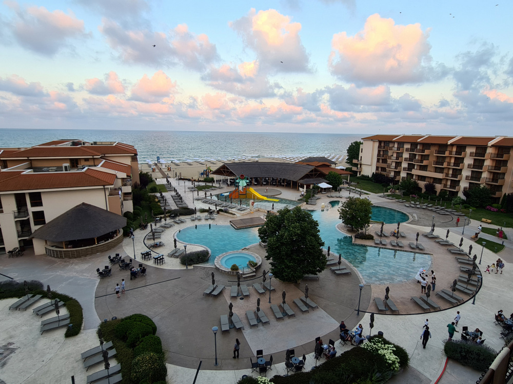 Piscine și clădiri hoteliere lângă mare, în lumina serii