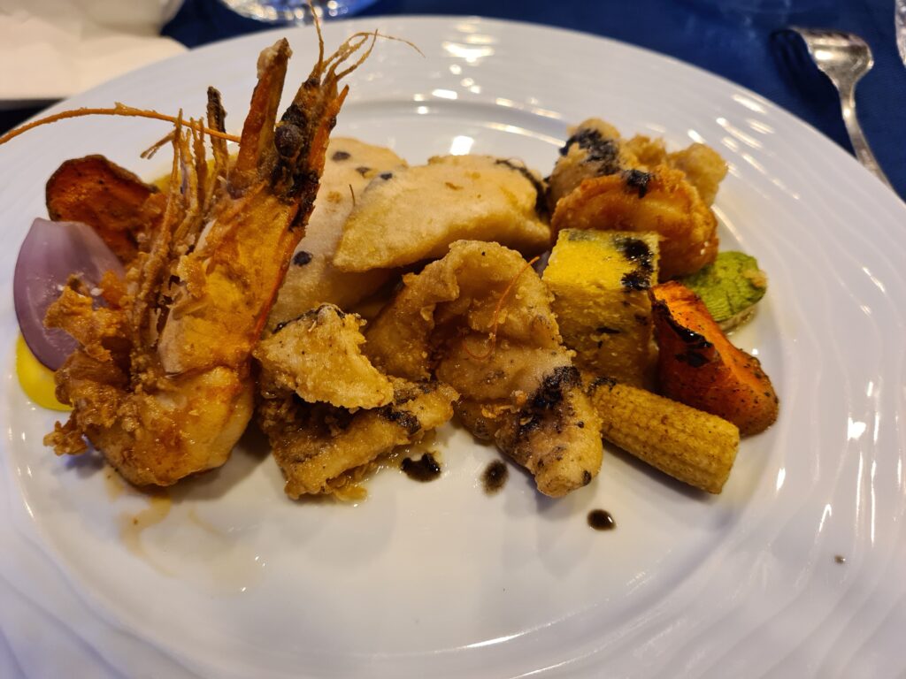 Fructe de mare rumenite și legume pe o farfurie albă
