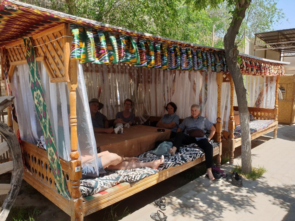 Oameni odihnindu-se într-un pavilion din lemn cu textile colorate