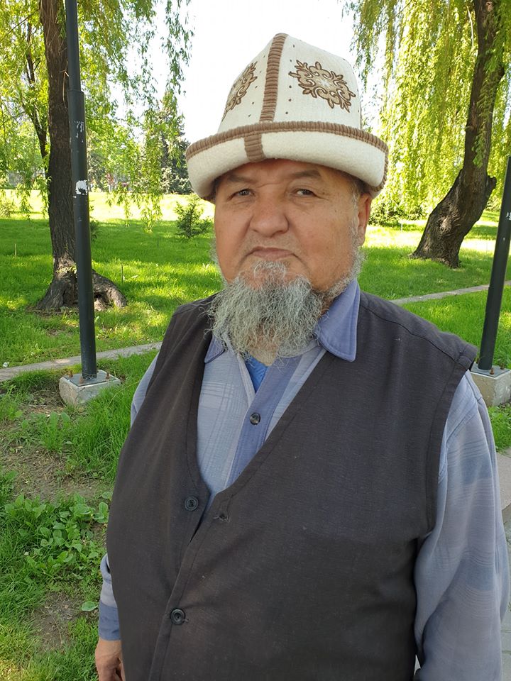 Bărbat cu barbă purtând pălărie tradițională albă într-un parc