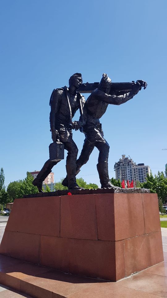 Monument din bronz cu două personaje pe soclu roșu
