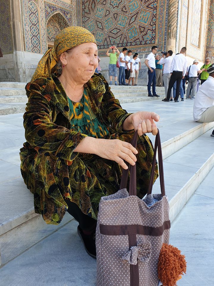 Femeie așezată pe trepte lângă o intrare decorată