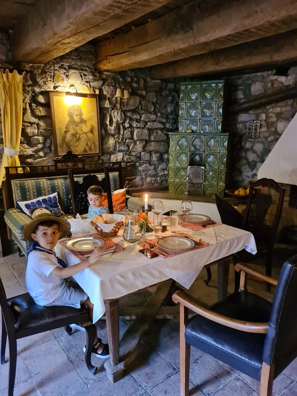 Copil la o masă pregătită într-o încăpere cu pereți din piatră.