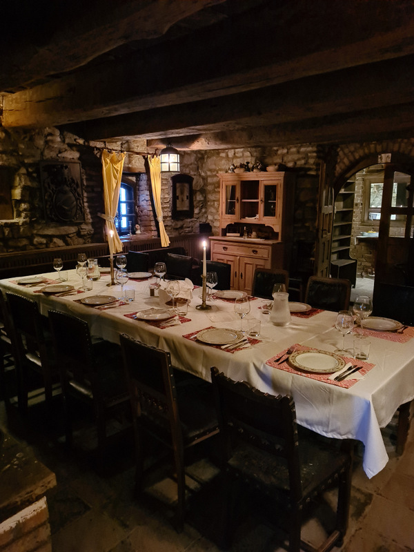 Masă lungă pregătită pentru cină într-o încăpere rustică din piatră.