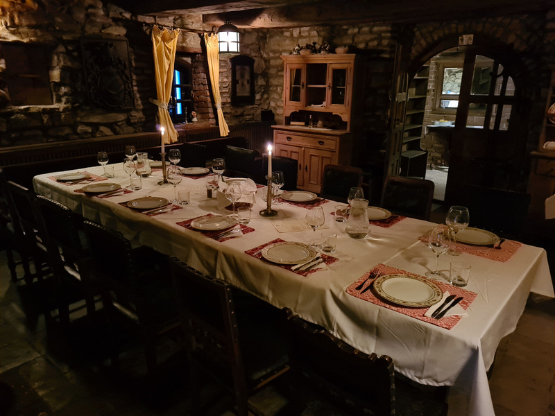Masă lungă pregătită pentru cină într-o sală rustică din piatră