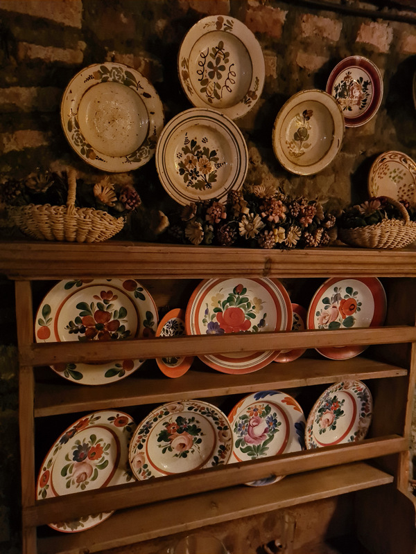 Farfurii ceramice pictate expuse pe perete și pe un raft din lemn.