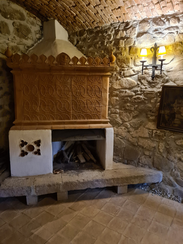 Vatră cu hotă decorată într-o încăpere cu pereți din piatră.