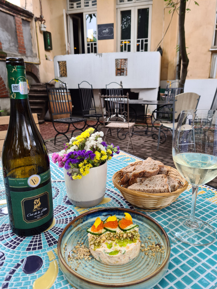 Masă în curte cu vin, aperitiv, pâine și flori.