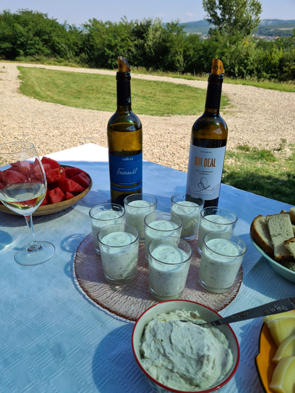 Masă în aer liber cu sticle de vin, pahare și gustări.