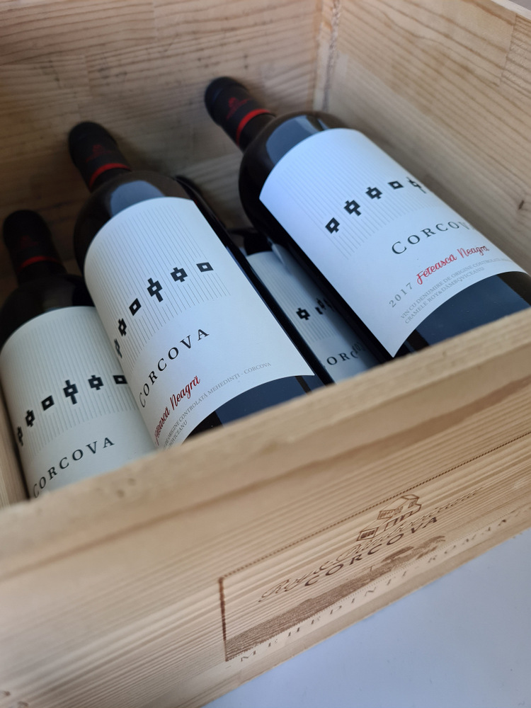 Două sticle de vin cu etichete albe într-o cutie de lemn.