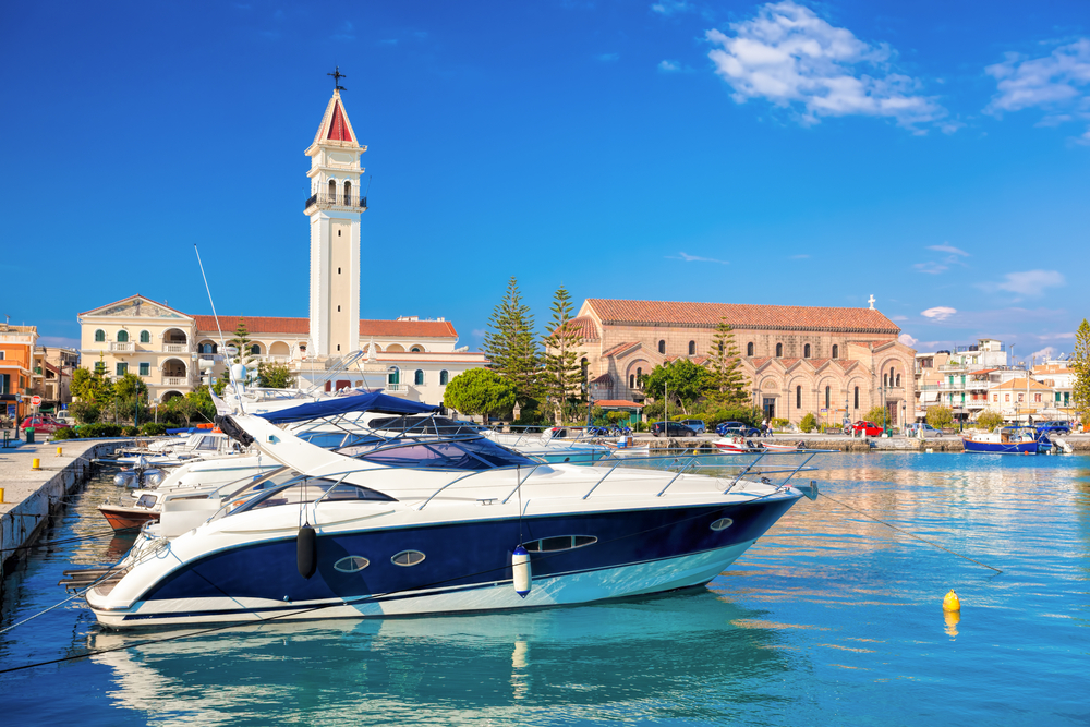 Iaht ancorat în port, cu turn de biserică în fundal