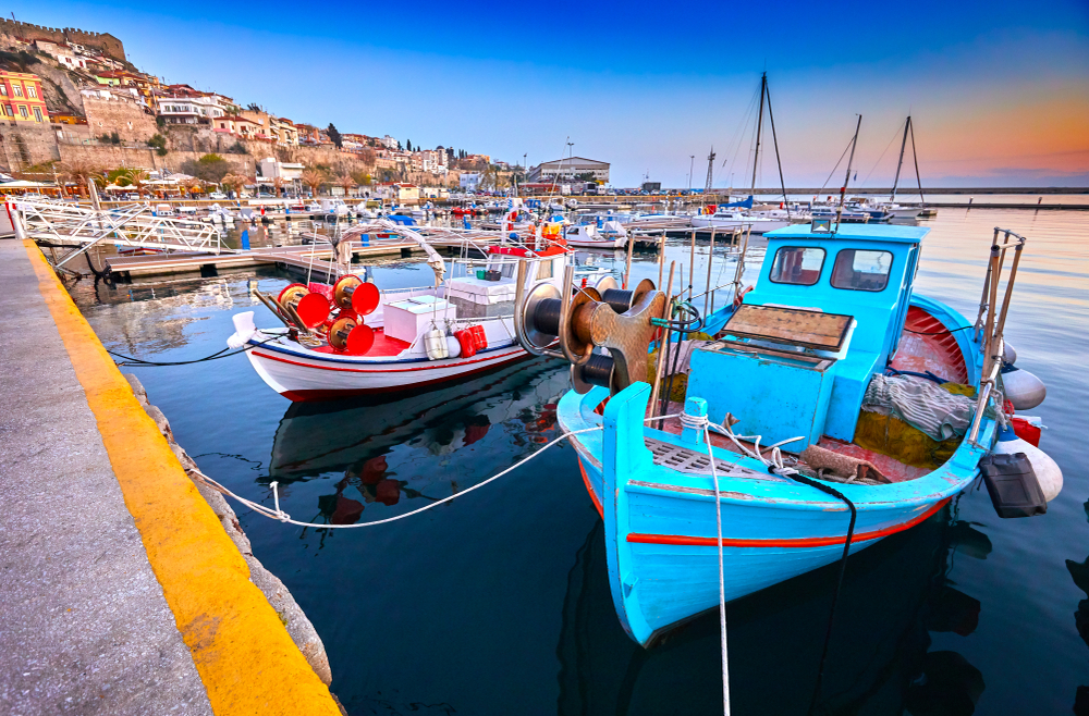 Bărci de pescuit colorate acostate într-un port la apus.