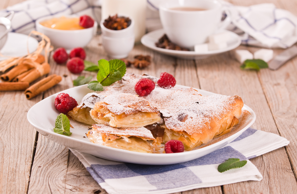 Produse de patiserie pudrate cu zahăr, alături de zmeură și cafea.
