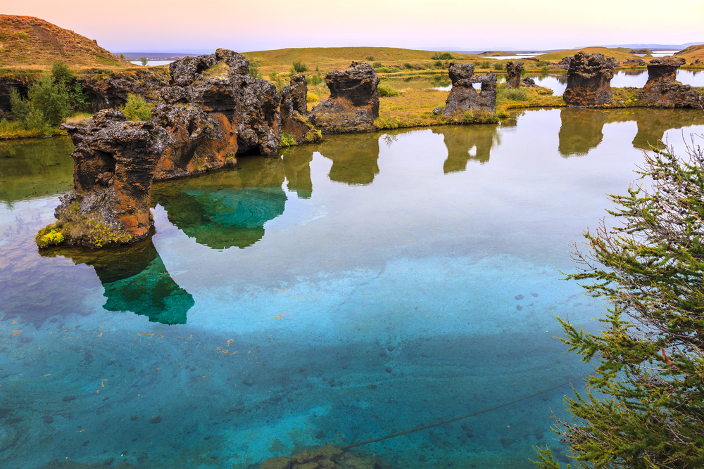 Formațiuni stâncoase cu arcade reflectate în apa unui lac