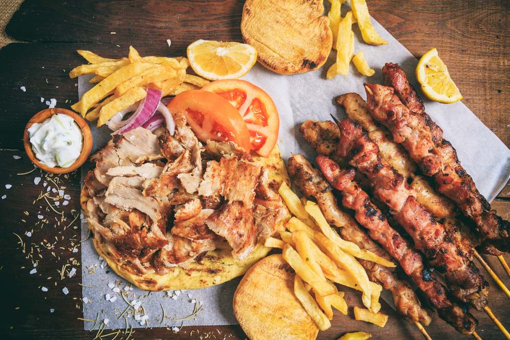 Platou cu carne la grătar, frigărui, cartofi prăjiți și legume.