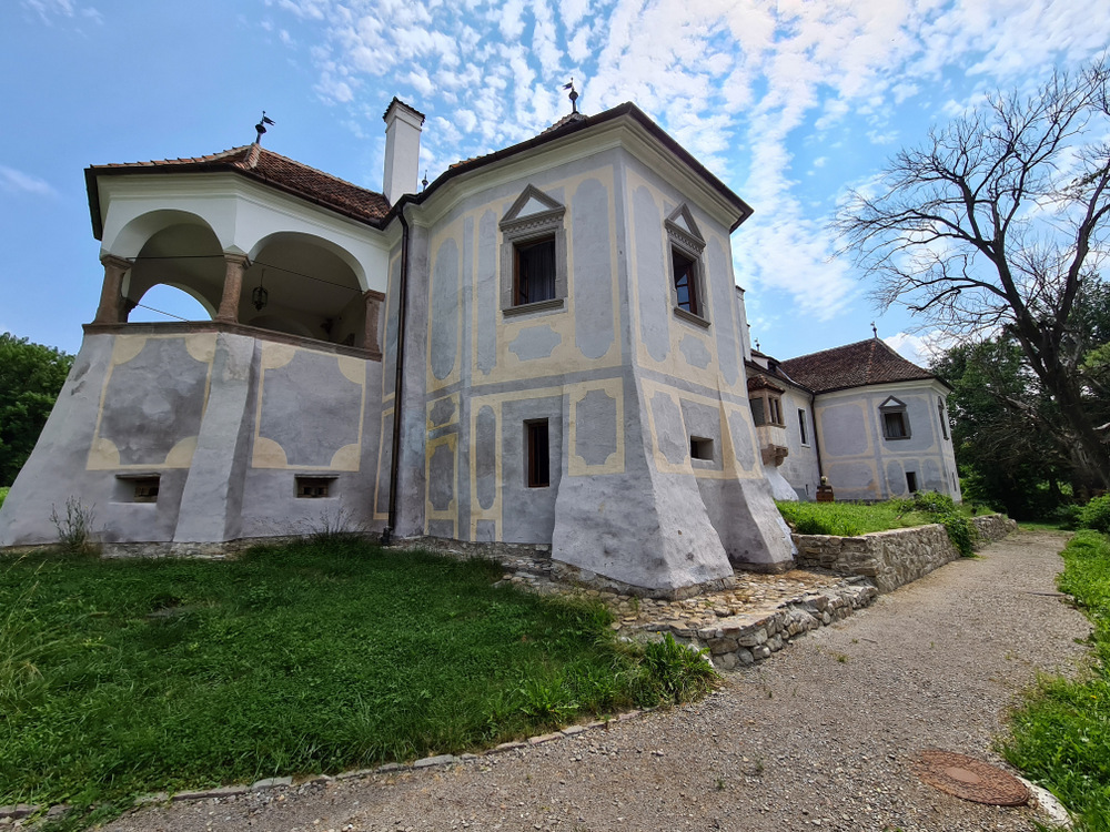 Clădire istorică albă cu pridvor arcuit și alee de pietriș