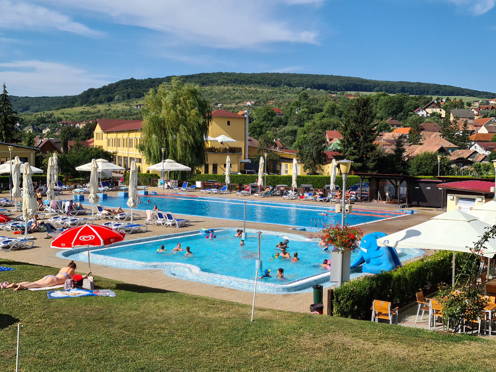 Bazine exterioare cu apă albastră, umbrele și șezlonguri