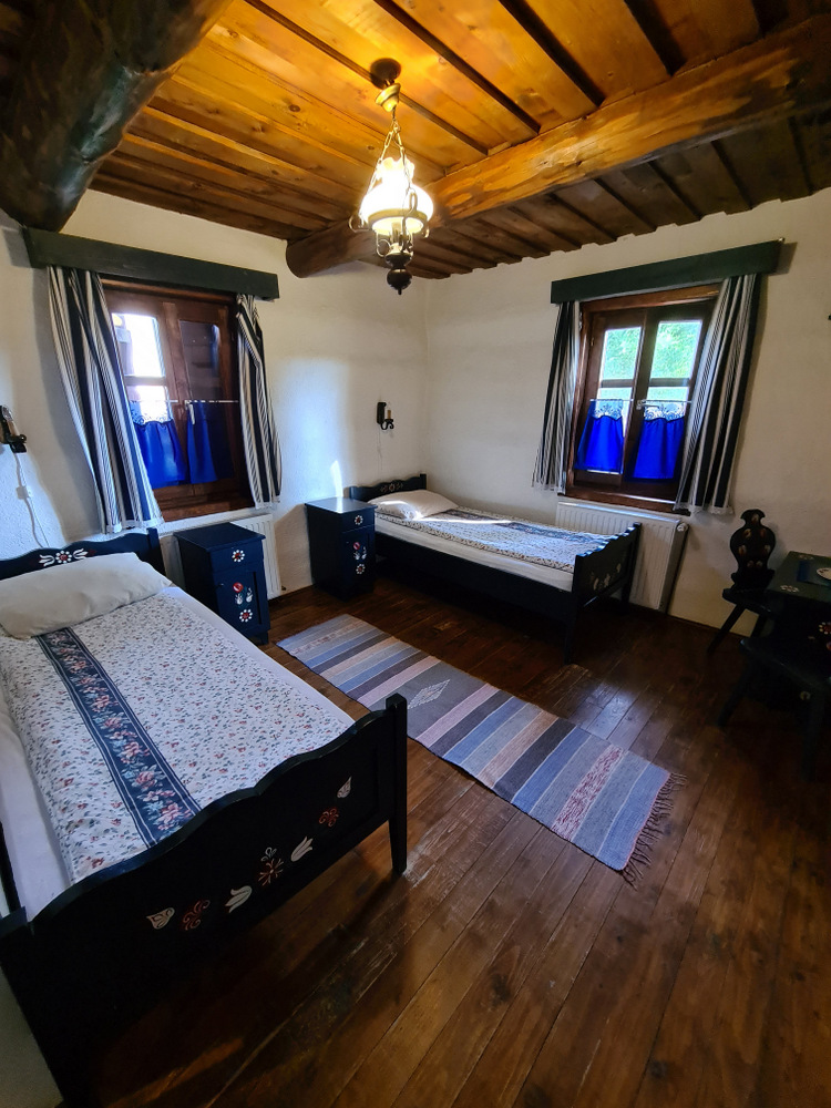 Cameră tradițională cu paturi înguste și ferestre cu perdele