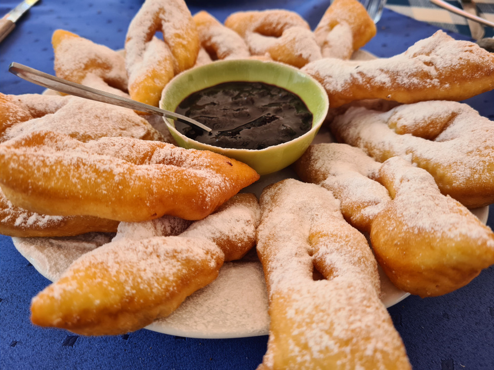 Produse de patiserie pudrate cu zahăr, lângă un bol cu gem
