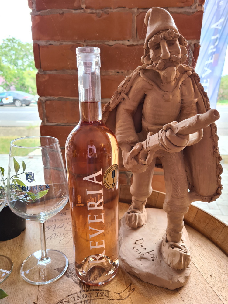 Sticlă de vin rosé lângă o sculptură din lemn