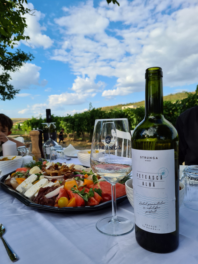 Sticlă de vin alb lângă pahare și platou cu aperitive
