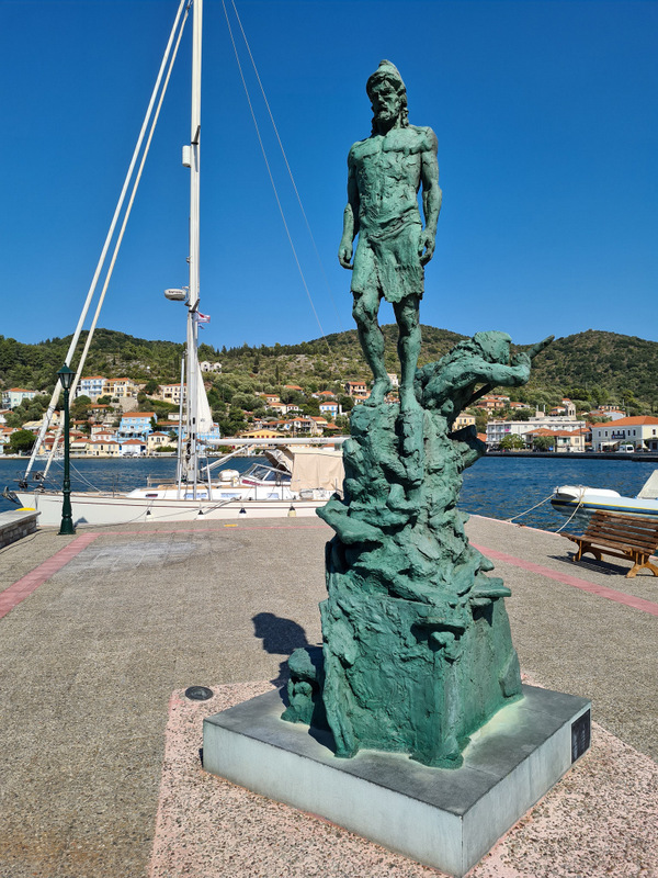 Statuie din metal verde pe un soclu lângă port